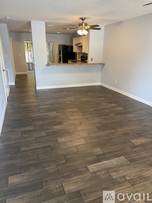 A spacious room with wooden flooring and a ceiling fan.
