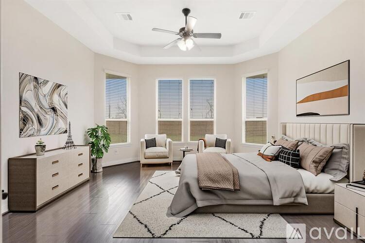 A bedroom with a large bed, a ceiling fan, and a painting on the wall.