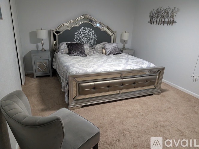 A bedroom with a large bed, a chair, and a nightstand.