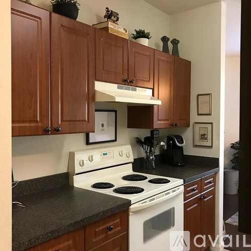 A kitchen with a white stove top oven and wooden cabinets.