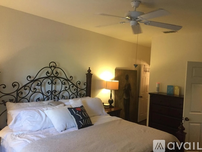 A bedroom with a bed, a lamp, and a fan.