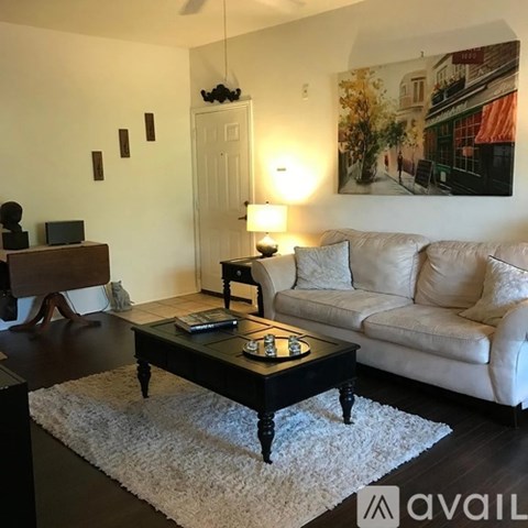 A living room with a white couch, a coffee table, and a painting on the wall.