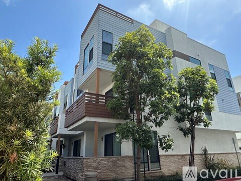A modern two-story house with a balcony and a stone wall.