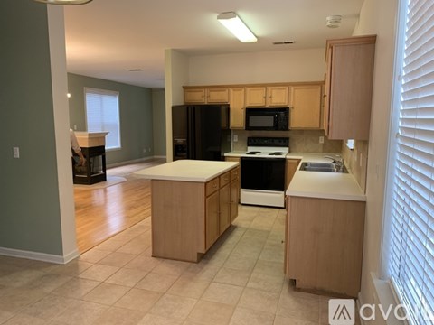 A kitchen with wooden cabinets and a black refrigerator.