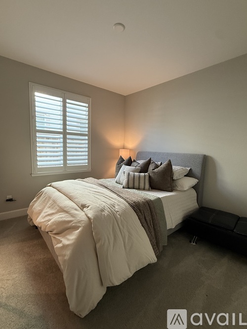 A bedroom with a bed, pillows, and a lamp.