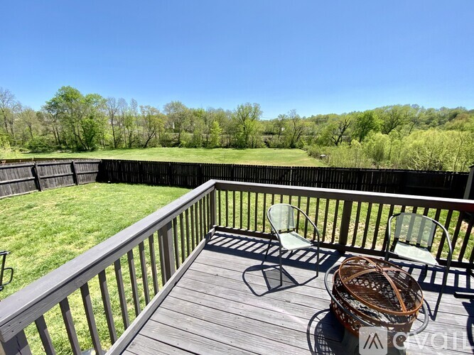A deck with a chair and table is overlooking a grassy area.