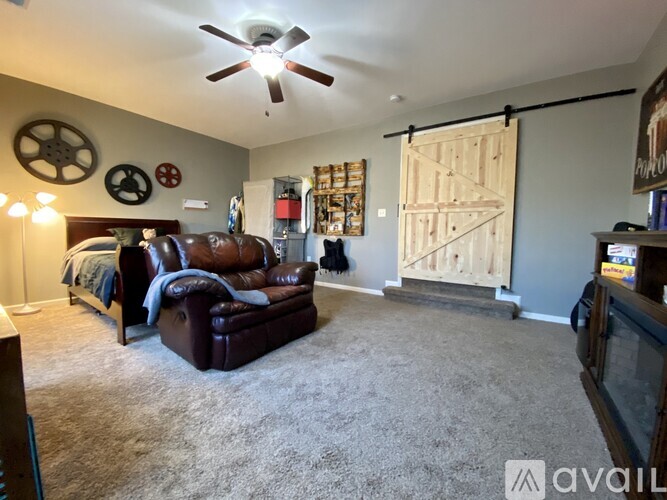 A living room with a brown leather couch and a ceiling fan.