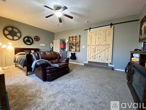 A living room with a brown leather couch and a ceiling fan.