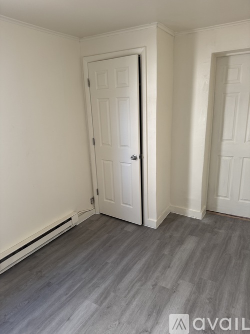 A room with a white door and grey flooring.