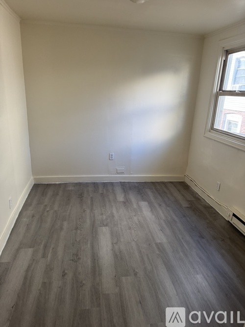 A room with wooden flooring and a window.