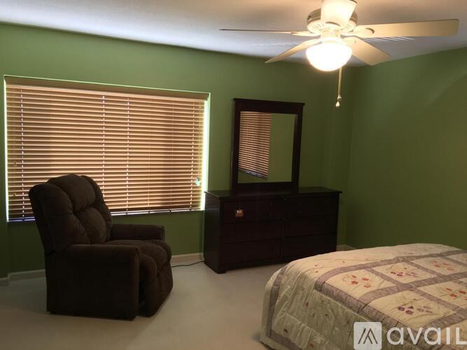 A bedroom with a brown chair, a bed, and a dresser.