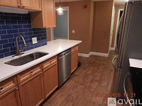 A kitchen with wooden cabinets and a blue tile backsplash.