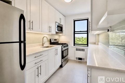 A kitchen with white cabinets and a black fridge.