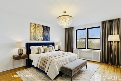 A bedroom with a large bed, a chandelier, and a window with curtains.