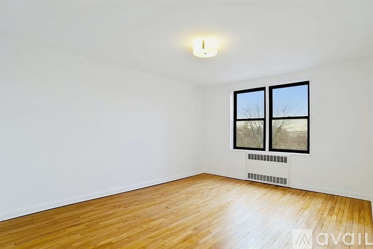 A room with wooden floors and a window with a view of trees outside.