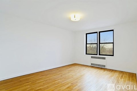 A room with wooden floors and a window with a view of trees outside.