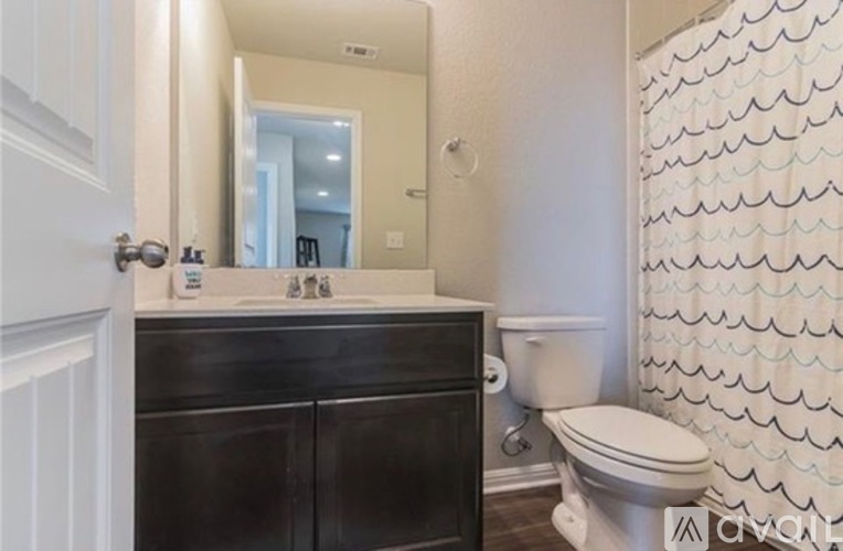 A bathroom with a toilet, sink, and shower curtain.