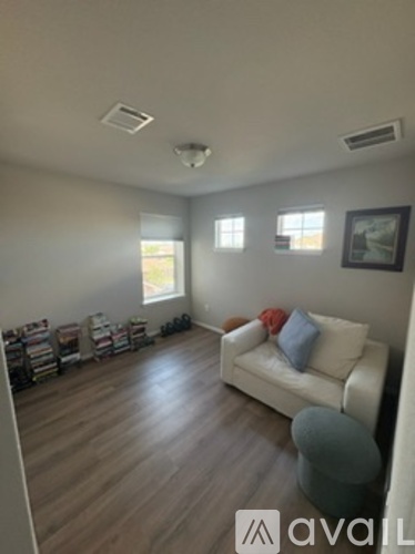 A living room with a white couch and a blue ottoman.