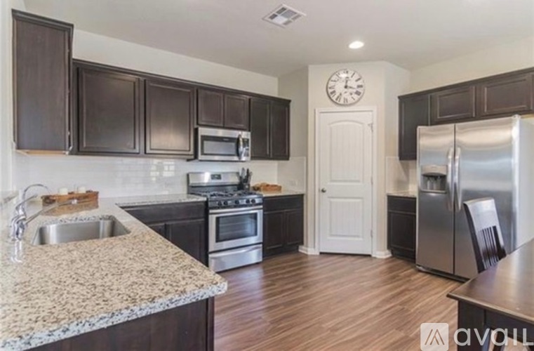 A kitchen with dark brown cabinets and a granite countertop.