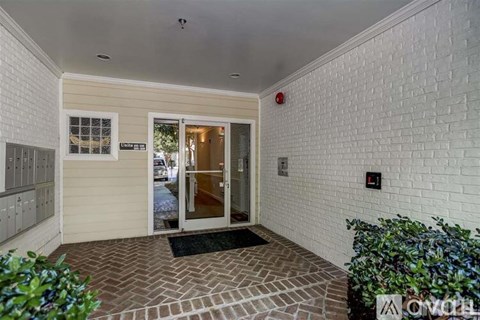 A white brick wall with a door and a red light on it.