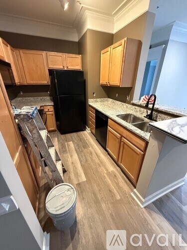 A kitchen with wooden cabinets and a black fridge.