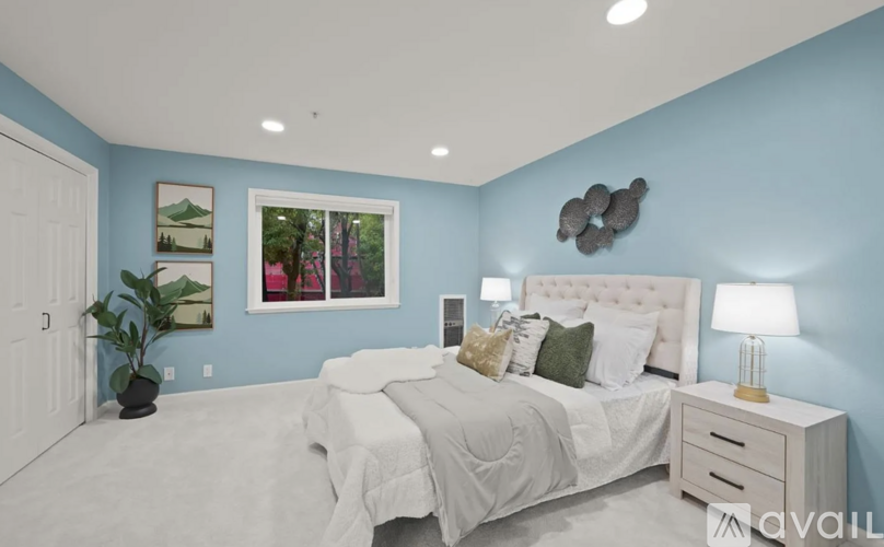 A bedroom with a white bed, a white nightstand, and a picture on the wall.