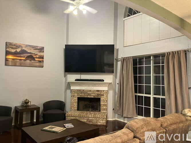 A living room with a fireplace, a television, and a painting on the wall.