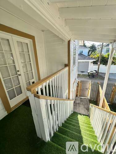A staircase with white railings and a green carpet.