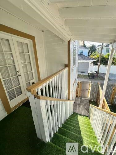 A staircase with white railings and a green carpet.
