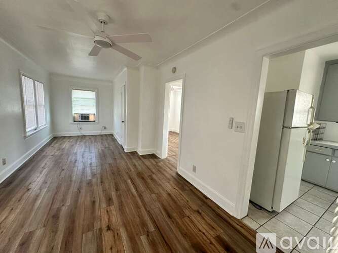 A spacious room with wooden floors and a ceiling fan.