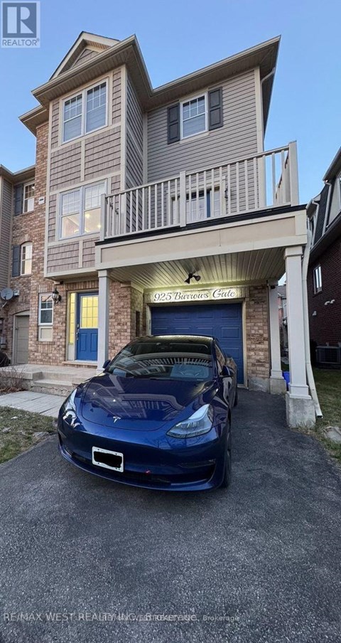 A blue car is parked in front of a two-story building with a garage.