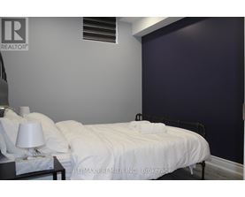 A bedroom with a white bed and a lamp on the nightstand.