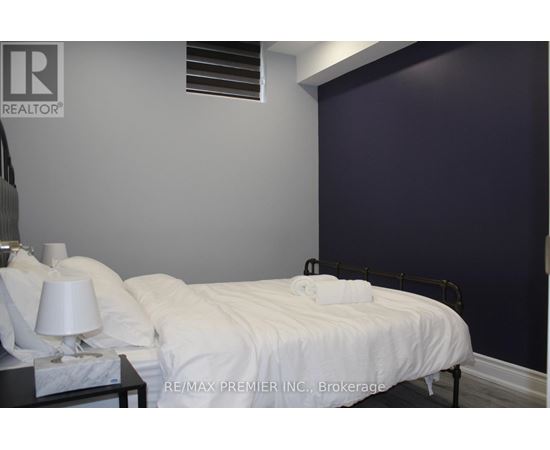 A bedroom with a white bed and a lamp on the nightstand.