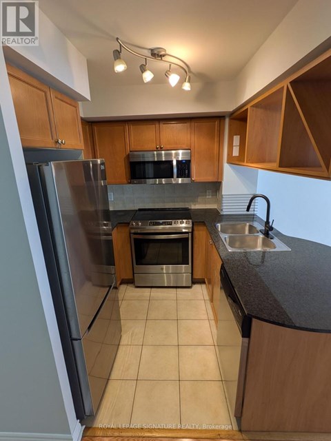 A kitchen with wooden cabinets and a stainless steel refrigerator.