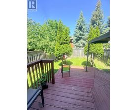 A wooden deck with a table and chairs overlooking a lush green backyard.