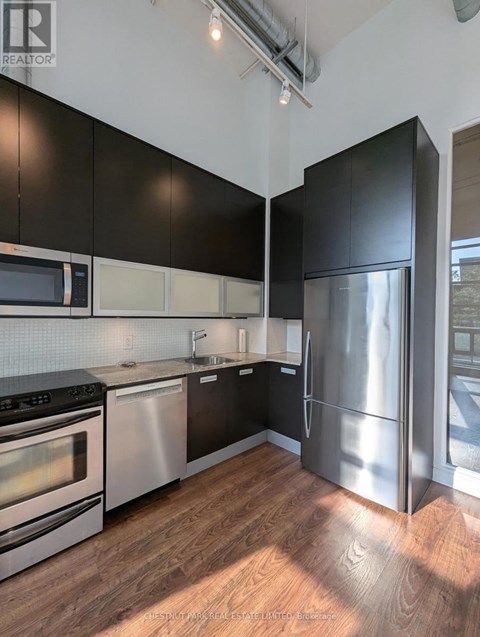 A modern kitchen with black cabinets and stainless steel appliances.