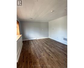 A room with wooden flooring and white walls.