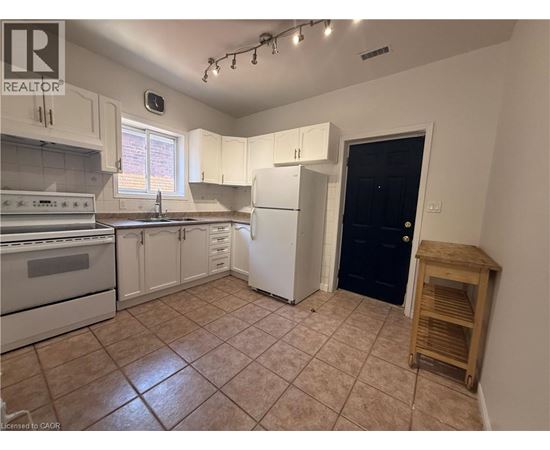 A kitchen with white cabinets and a black door.