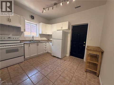 A kitchen with white cabinets and a black door.