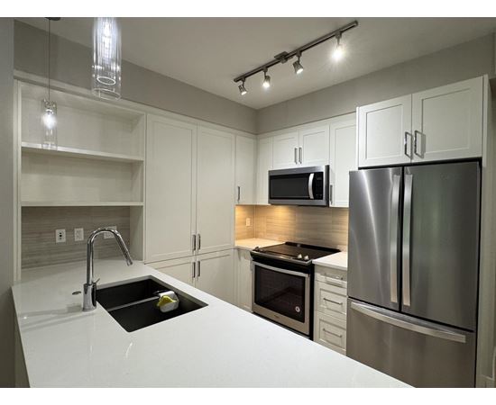 A modern kitchen with a stainless steel refrigerator and microwave.