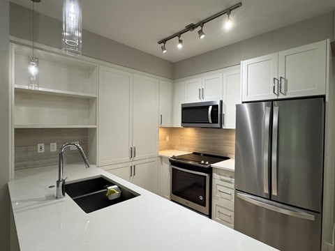 A modern kitchen with a stainless steel refrigerator and microwave.