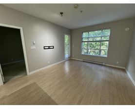 A room with wooden flooring and a window with a view of trees.