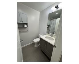 A bathroom with a toilet, sink, and mirror.