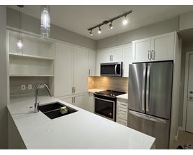A modern kitchen with stainless steel appliances and white countertops.