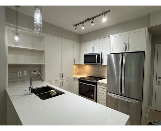 A modern kitchen with stainless steel appliances and white countertops.