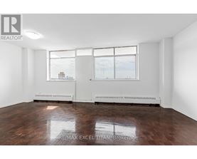 A large empty room with a window overlooking a cityscape.