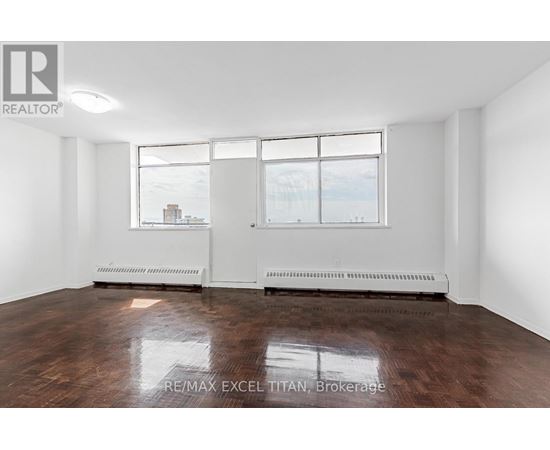 A large empty room with a window overlooking a cityscape.