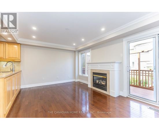 A well-lit, empty living room with a fireplace and wooden floors.