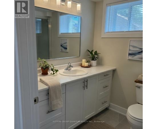 A bathroom with a white toilet, sink, and cabinets.