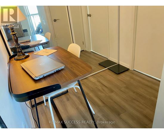 A room with a desk, laptop, chair, and a lamp.